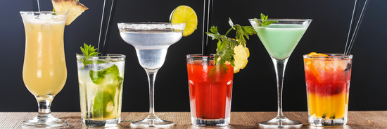 row of flower cocktails in multitude of colours and in different kinds of glasses against a black background