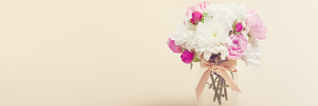 image of pink and white blooms in vase on beige background for how to choose the right vase for flowers
