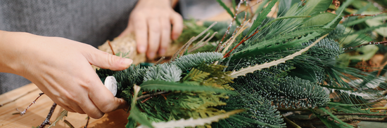 hands putting together pine needles for christmas flower arrangement