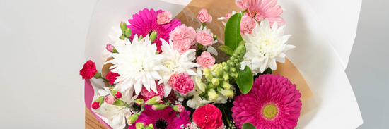 extreme close up of bright pink, white, light pink and red flown not grown flowers wrapped in white and brown paper