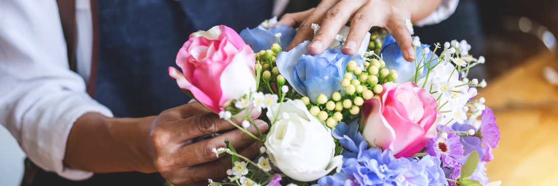 brisbane florists hands arranging multicoloured roses with baby's breath into an arrangement