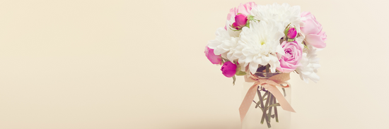 image of pink and white blooms in vase on beige background for how to choose the right vase for flowers