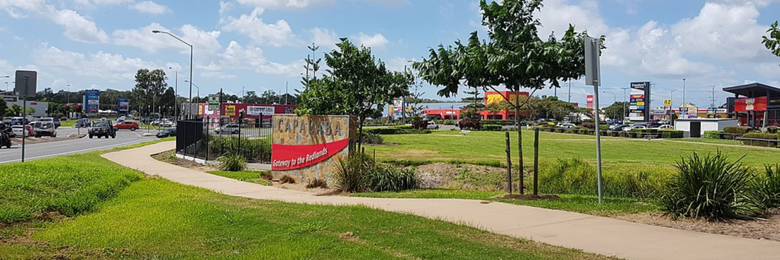 image of Capalaba town centre with green lawns, a Capalaba sign and a path going through for Redlands florist