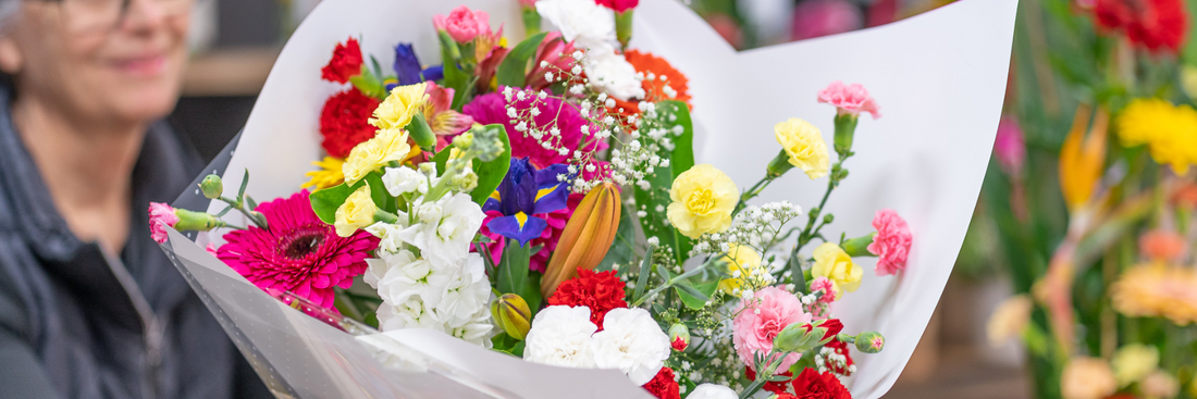 image of redlands florist holding an arrangement of seasonal flowers wrapped in white paper