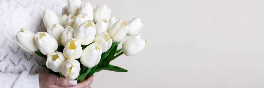 hands holding a bunch of beautiful white tulips in a sympathy flowers brisbane bouquet against a white background